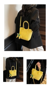 Detail of yellow lychee leather handbag with horse charm and dual round handles