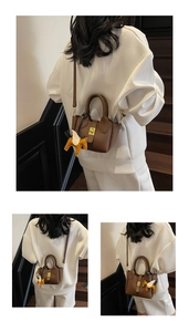 Détail du mini sac seau marron à grain de litchi avec breloque pégase et fermoir doré