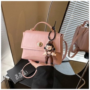 Dettaglio di una borsa a tracolla in pelle rosa cerata con chiusura a scatto ovale dorata