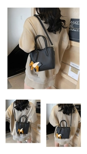 Detail of black lychee grain leather handbag with horse charm and Little Dandelion logo