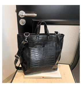 Detail of crocodile pattern faux leather tote bag featuring a skull embossed patch
