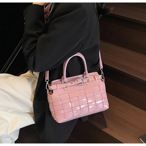 Dettaglio della borsa a secchiello intrecciata rosa con texture lucida e fibbia in metallo