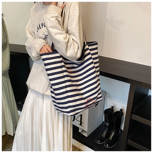 Detail view of large canvas tote bag with blue and white stripes and red embroidery