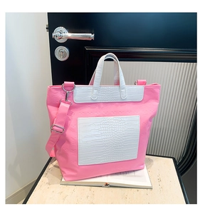 Detail view of pink tote bag with embossed skull patterns and white faux crocodile texture