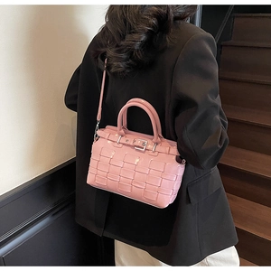 Borsa a secchiello rosa intrecciata con fibbia in metallo indossata su blazer scuro