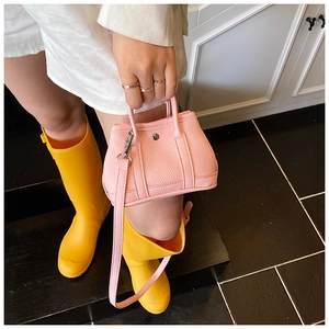 Detail of pink mini leather handbag with lychee texture and metallic round buckle