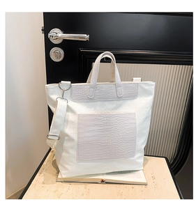 Close-up of white tote bag with skull embossed texture and grey crocodile pattern accents