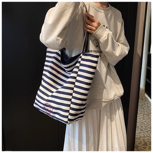 Detail of blue and white striped canvas tote bag with dog embroidery and text