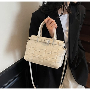 Borsa a secchiello intrecciata beige abbinata a un blazer nero oversize su scale