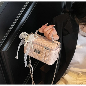 Detail of pink quilted box bag with lace pearl bow charm and chain strap