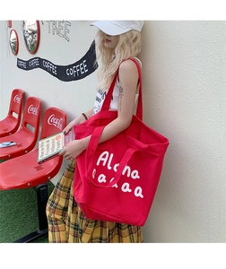 Outdoor street style shot of a large red canvas tote bag with white Aloha print