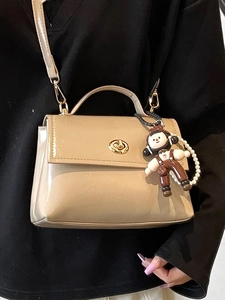 Borsa a mano beige in pelle lucida con chiusura dorata e ciondolo con perle