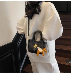 Détail du sac seau noir en cuir litchi avec boucle dorée et breloque pégase jaune