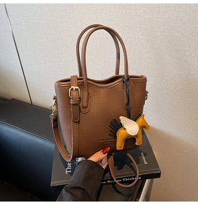Detail of lychee textured leather bucket bag with yellow pegasus charm and handle