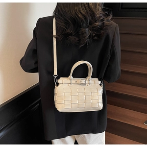 Dettaglio della borsa a secchiello beige intrecciata con manici e tracolla regolabile