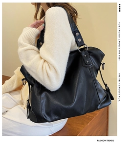 Detail of black leather tote bag with wide straps and silver metal rivet decorations