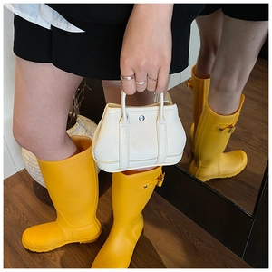 Mini white litchi pattern leather handbag paired with bright yellow rubber rain boots