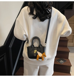 Détail du sac seau noir en cuir grainé avec fermoir doré et breloque petit cheval