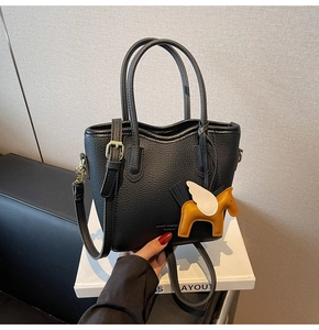 Close-up of black lychee grain leather bucket bag with a yellow leather horse charm