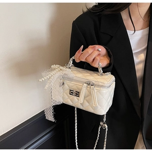 Close-up of quilted white mini box bag featuring lace detail and pearl pendant decor