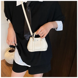 Detailed macro view of white lychee textured leather mini handbag with metal ring handle