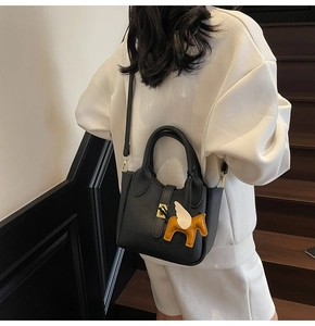 Détail du sac seau en cuir grainé avec charm pégase jaune et fermoir doré élégant