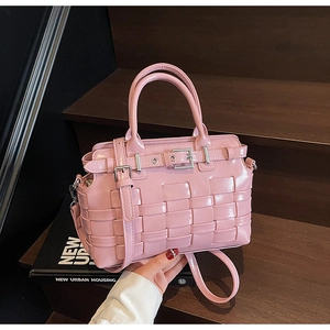 Dettaglio di borsa a secchiello in vernice rosa con trama intrecciata larga e fibbia