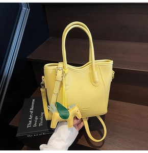 Detail of yellow lychee texture leather handbag with Pegasus charm on wooden stairs