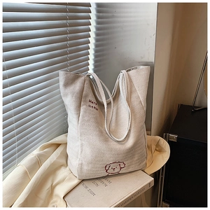 Close-up of cream canvas tote bag featuring red dog embroidery and sturdy shoulder straps