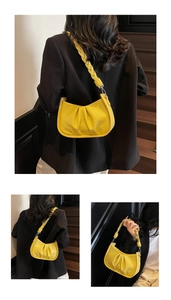 Detail of a bright yellow pleated moon bag featuring woven shoulder straps and pebble leather