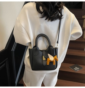Détail du sac seau noir en cuir litchi avec fermoir doré et charm de cheval orange