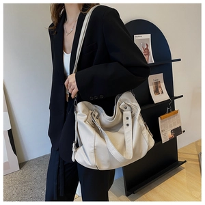 Detail of minimalist beige soft leather tote bag worn with a professional black suit