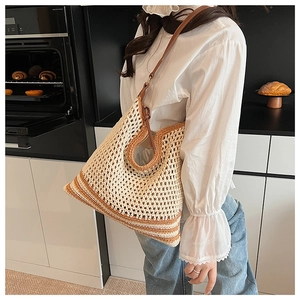 Detail of beige crochet woven tote bag featuring brown leather straps in a kitchen setting