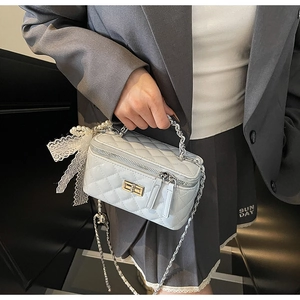 Quilted light blue box bag with silver chain strap and pearl bow detail on a stylish outfit