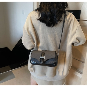 Detail view of contrast stitching small square bag with textured flap and silver buckle
