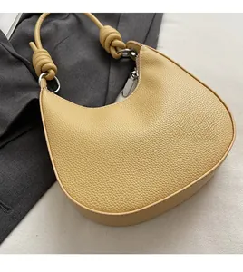 Dettaglio borsa hobo gialla con texture litchi e manico annodato con anello argento