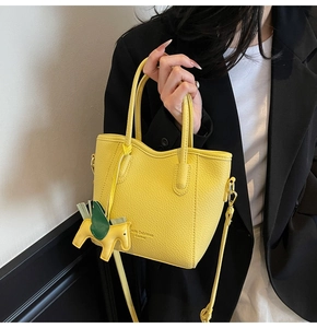 Close-up of yellow leather handbag featuring a horse charm and textured lychee pattern