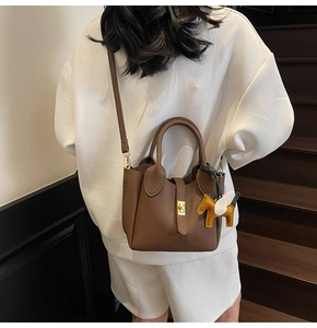 Détail du sac seau en cuir grainé marron avec fermoir doré et breloque petit cheval