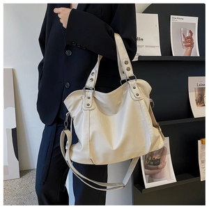 Detail of adjustable shoulder strap and metal rivets on beige large capacity tote bag