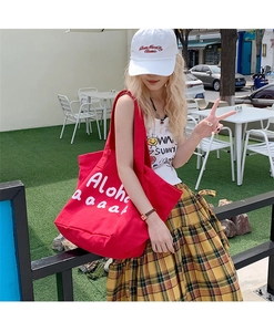 Close-up of red canvas tote bag with white Aloha print and textured fabric detail