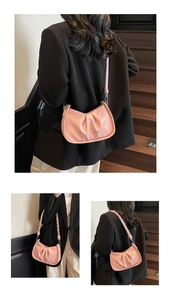Detail of pink ruched shoulder bag in pebble leather with woven handle and slim strap