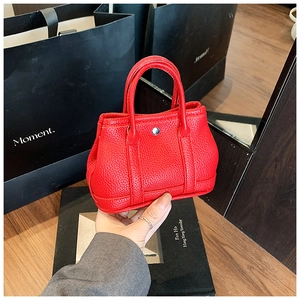 Detailed close-up of a red litchi texture mini handbag with silver metal button and handles