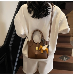 Détail du sac seau en cuir marron avec fermoir doré et accessoire petit cheval