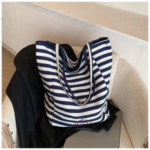 Detail of blue and white striped canvas tote bag with Snoopy embroidery on a white chair