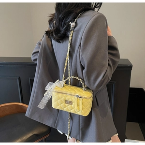 Detail of yellow quilted mini box bag with gold handle and lace pearl charms