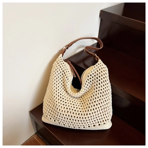 Detail of cream woven tote bag with brown leather straps on a wooden staircase
