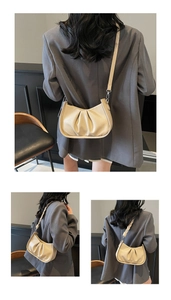 Detail of beige crescent bag featuring pleated texture and woven leather shoulder strap
