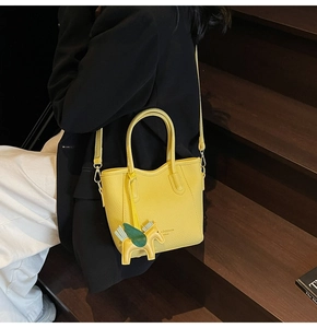 Detail of yellow pebble leather bucket bag with horse charm and adjustable strap