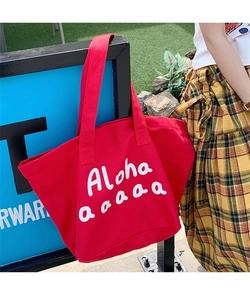 Detail of red canvas tote bag featuring white Aloha script print and wide shoulder straps