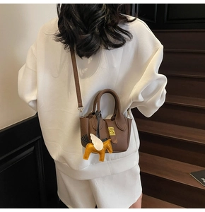Détail du sac seau en cuir marron foncé avec fermoir doré et breloque pégase jaune